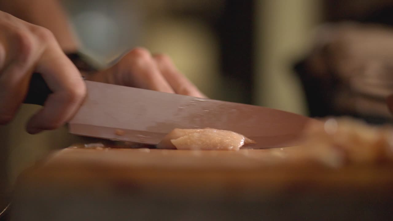 persona cortando el filete de pechuga de pollo en tiras con un cuchillo