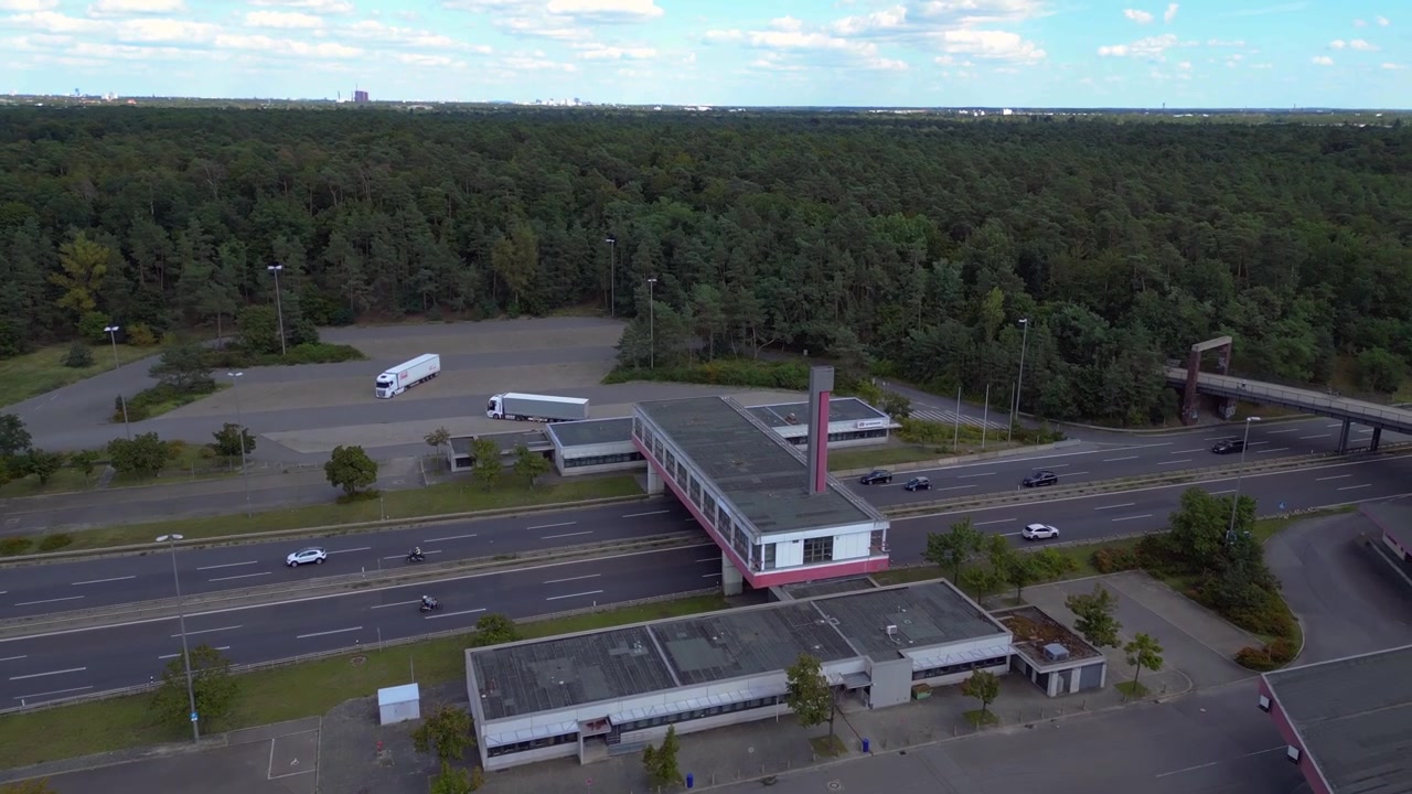 Area di sosta autostradale con auto che guidano su un'autostrada a più corsie. Veduta aerea dall'alto con drone.