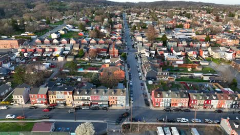 Stunning-panoramic-aerial-view-of-a-city,-including-houses,-businesses,-industrial-buildings,-several-city-blocks-and-hills-in-the-background-at-sunset