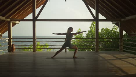 woman leaning into warrior pose in serene wooden cabana, yoga wellness sanctuary