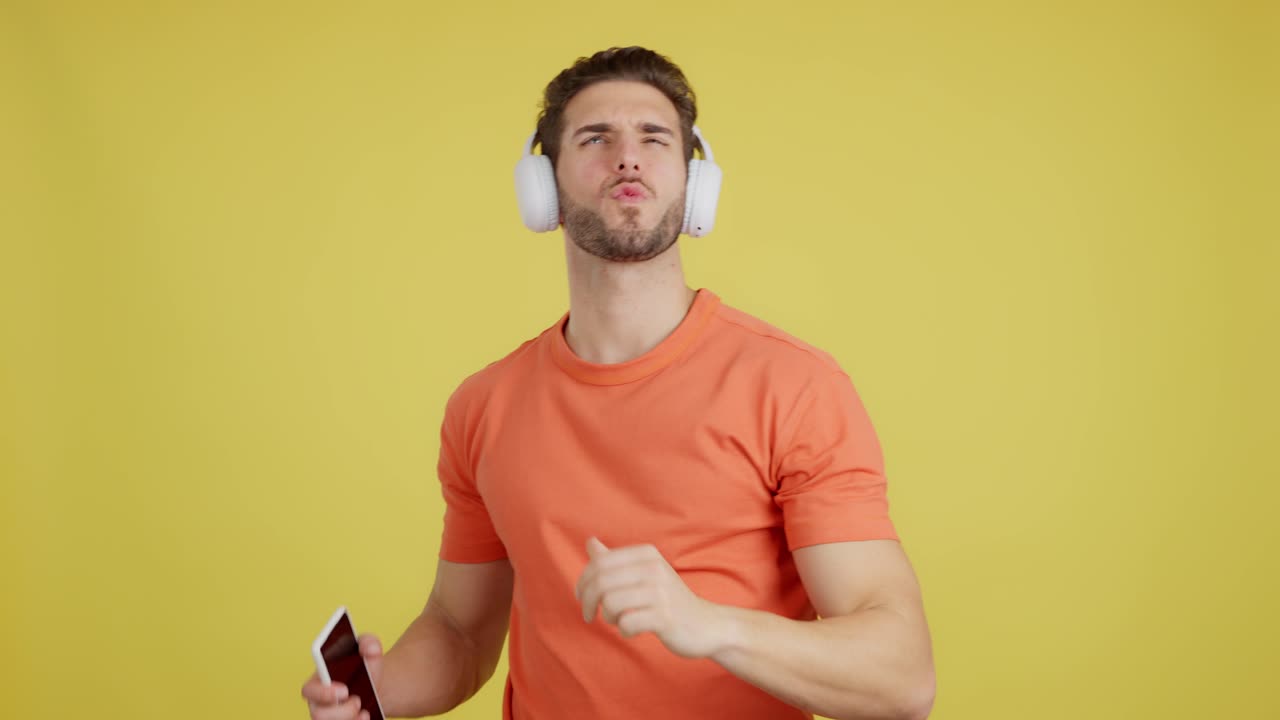 Young Man Expressing Different Emotions While Listening to Music with Headphones on Yellow Background