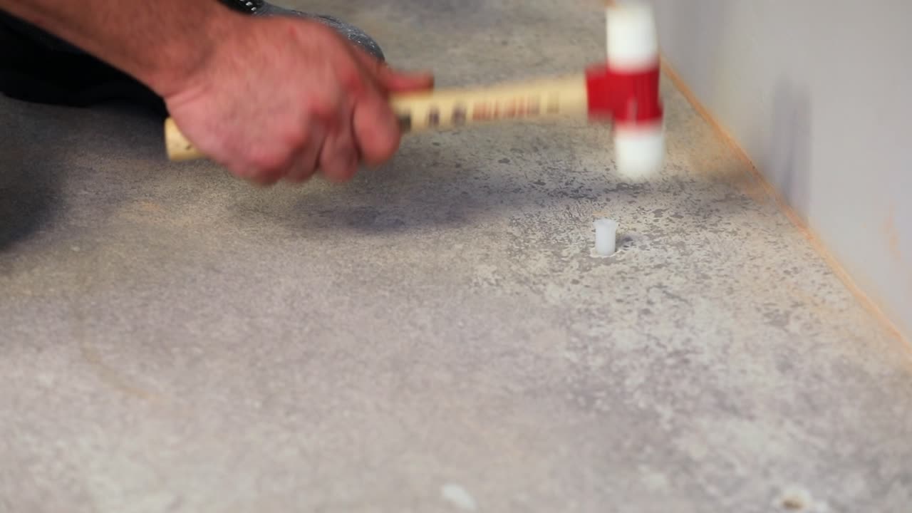 il lavoratore sta martellando i tasselli di plastica