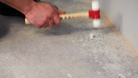 worker is hammering plastic dowels