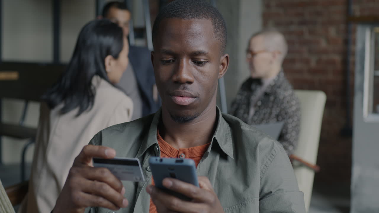 Businessman using mobile phone and credit card in an office setting