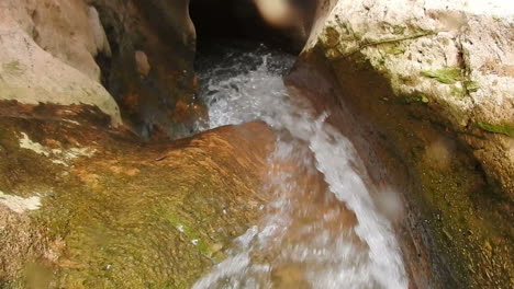 beautiful waterfall flows into natural pool surrounded by brown rock formation in national park tazakka , morocco