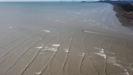 vista aérea del barco de pesca surfeando contra la ola hacia el mar en kuala muda, penang.