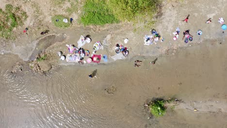 niños jugando en la orilla mientras las mujeres lavan ropa en las aguas del río masacre.