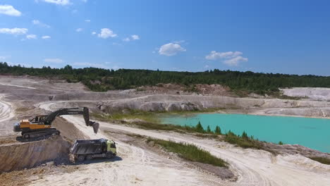 excavator loading the truck with kaolin. circle movement footage over the hilly territory of present day quarry.