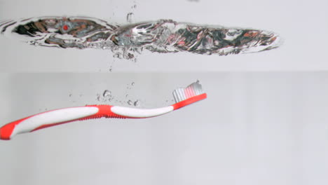 une brosse à dents en super ralenti tombant dans l'eau