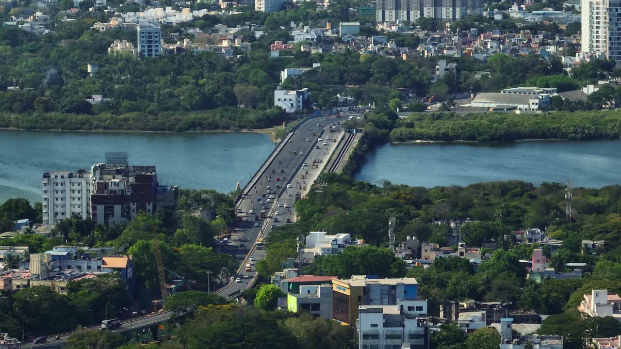 Aerial shot of a bridge with vehicles passing down joining the cities and cityscape at background.