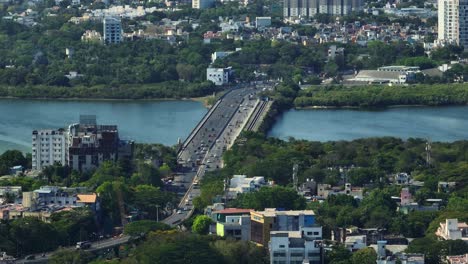 aerial shot of a bridge with vehicles passing down joining the cities and cityscape at background.