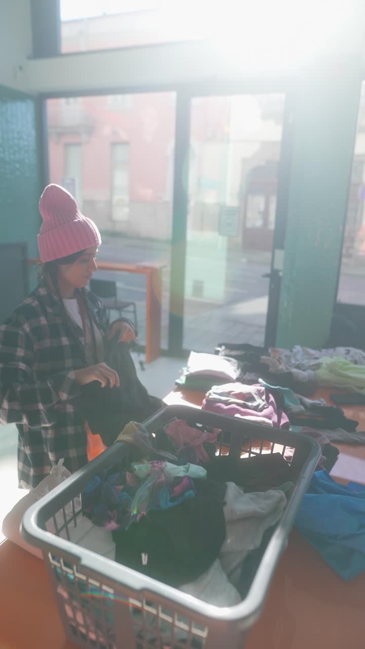 mujer clasificando ropa en un centro de donación