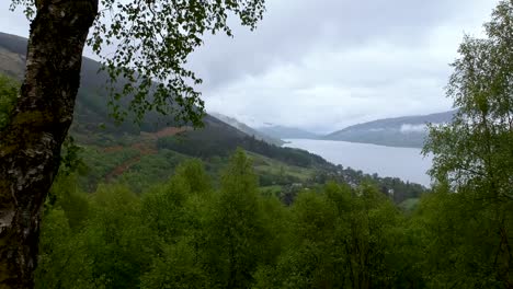 Cinematic-zoom-out-drone-shot-of-scottish-village-with-rainy-misty-clouds-over-it