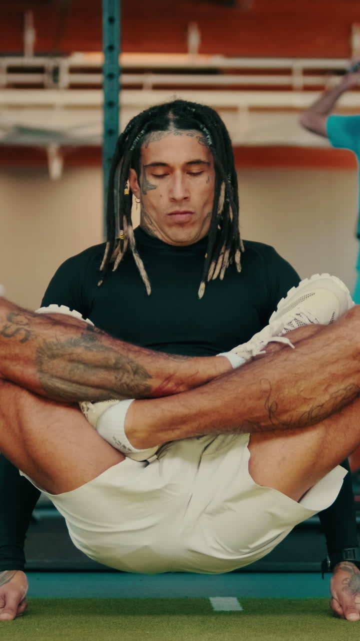 Homem Focado com Dreadlocks Alongando-se na Academia