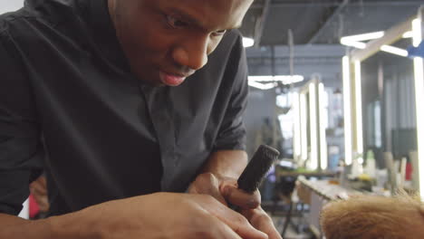 professional black barber giving beard trim to client