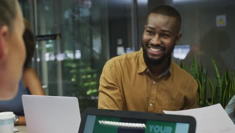 Diverse-male-and-female-business-colleagues-smiling-and-using-laptop