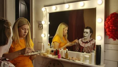 makeup artist applying scary clown makeup in a dressing room