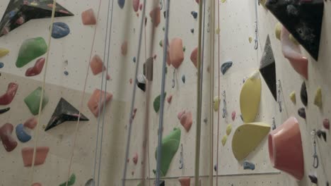 colorful rock climbing wall with various holds and ropes