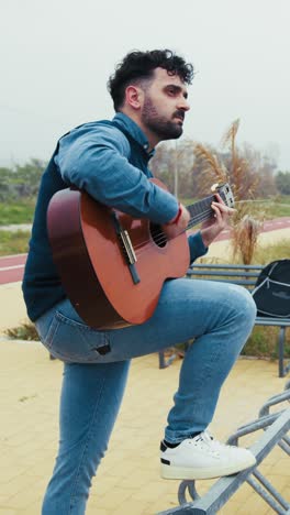 man plays the guitar facing the sea to relax