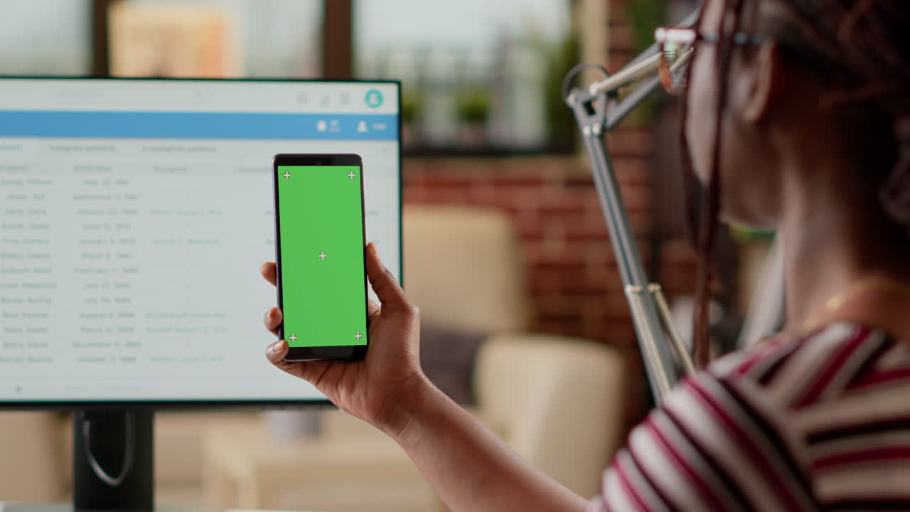 Person holding smartphone with green screen in medical setting