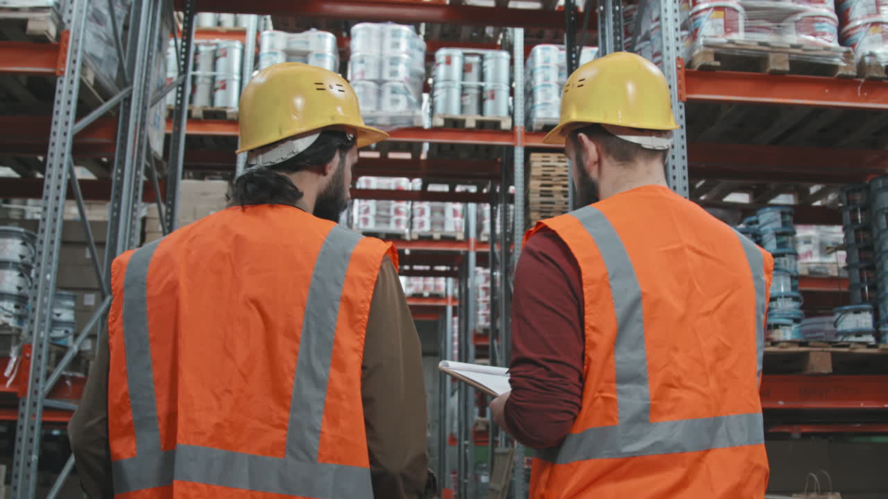 Workers in Hard Hats Walking Through Warehouse