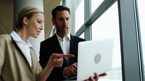 Businessman-and-woman-discussing-on-laptop