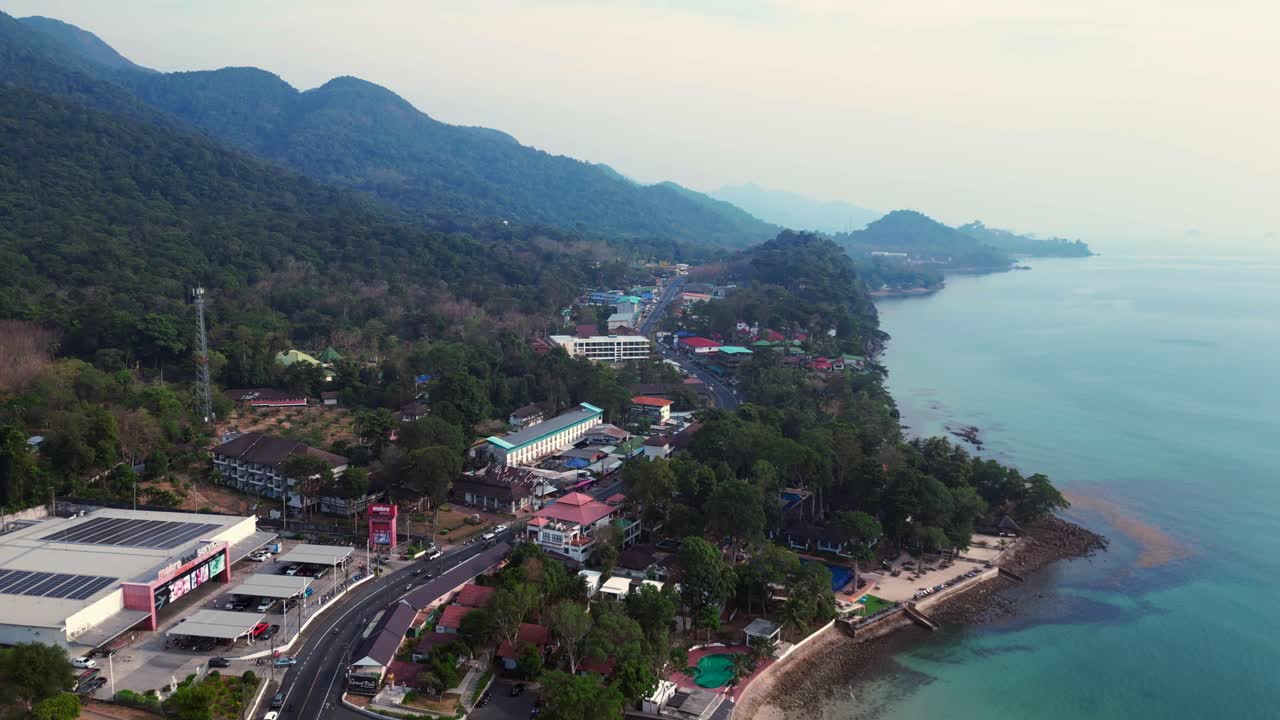 Road on Koh Chang, White Sand Beach Village, lush green hills. Marvelous aerial view flight static tripod hovering drone