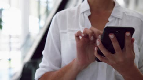 Businesswoman-using-mobile-mobile-phone-while-standing-near-escalator-in-a-4k