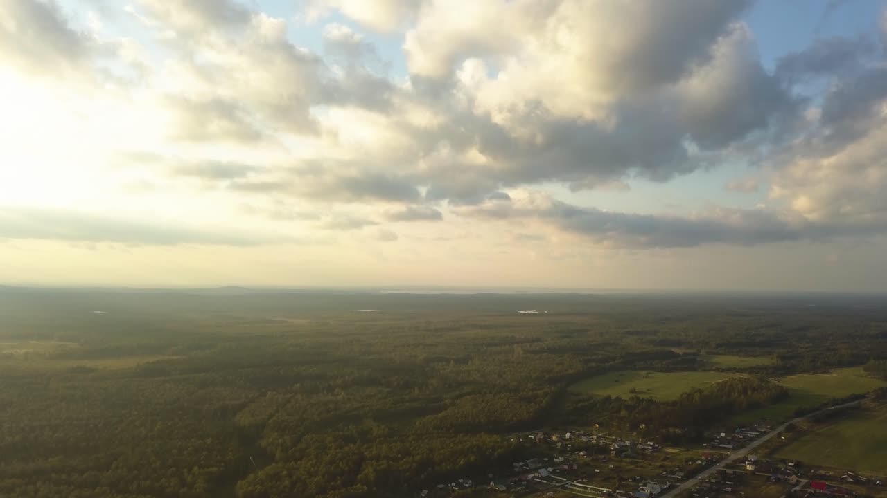 vista aérea de un paisaje rural con bosques, campos y casas al atardecer