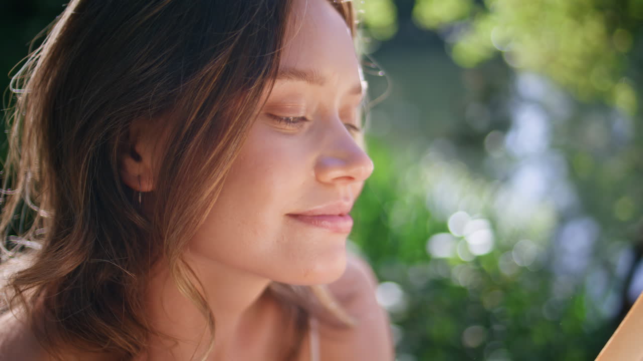Gentle woman posing camera at summer portrait. Lady holding flower reading book