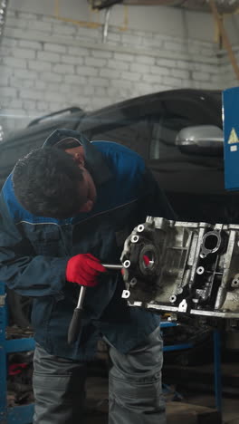 ingenieros automotores en un taller, uno trabajando atentamente en un motor mientras el otro está ocupado con su teléfono, iluminado por una luz brillante en el fondo