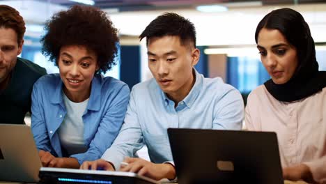 collaborative engagement: a diverse group of professionals sharing knowledge and insights while working on laptops, emphasizing teamwork and innovation in a modern workspace