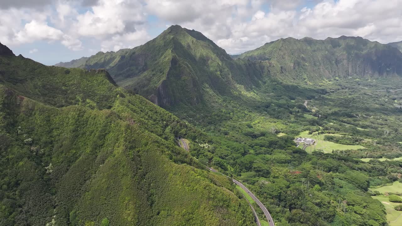 Aerial drone footage over Hawaii’s lush green mountains and tropical coastline, showcasing turquoise ocean waters, palm trees, scenic valleys, and the island’s vibrant natural landscapes from above