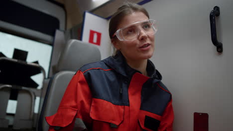 Smiling-professional-paramedic-discussing-work-with-colleague-in-emergency-car