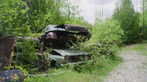 tirar de un tiro de coches destrozados apilados uno encima del otro luego mostrando un camino de tierra abandonado