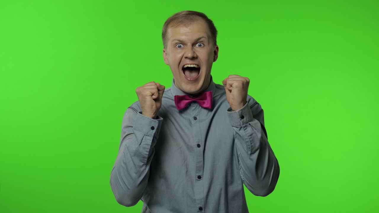 hombre ganando en la lotería, levantando las manos para la victoria, abriendo la boca de asombro, mirando conmocionado