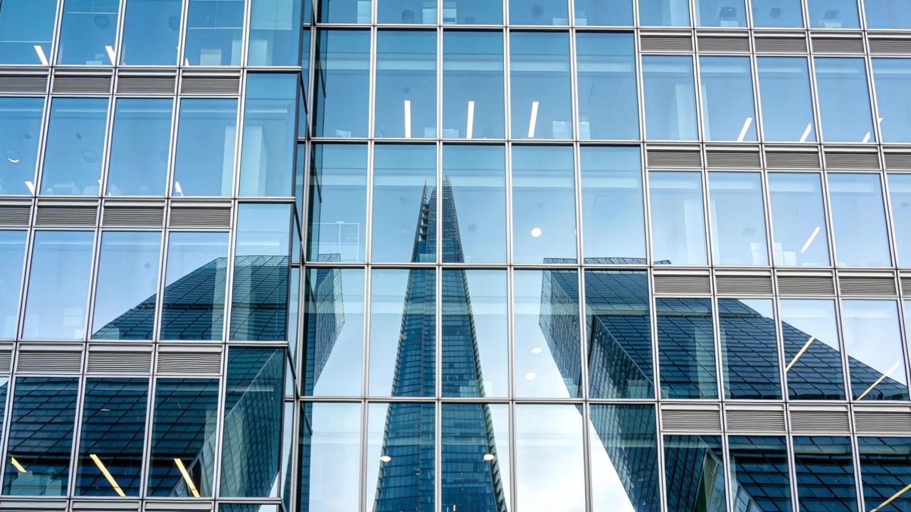 Torre central espelhada balançando após o movimento da câmera em uma parede de vidro, mostrando torres laterais e luzes.