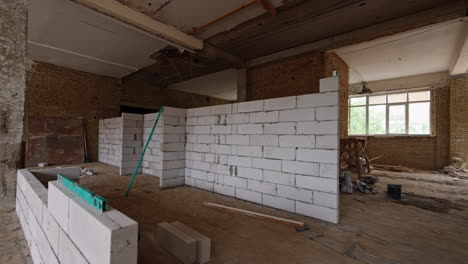 a wall of big white brick is added in the premise with red brick walls. large room in the building under construction.