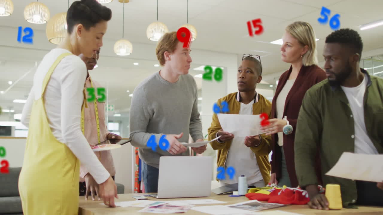 Numbers in various colors animation over diverse business team discussing documents
