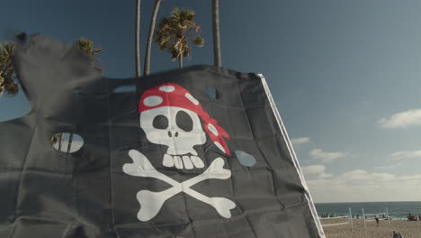 pirate flag waving in the wind with palm trees and beach in the back ground in cinematic slow motion