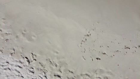 Aerial-Birds-Eye-View-Over-Quiet-Beach-With-Footprints-In-The-Sand