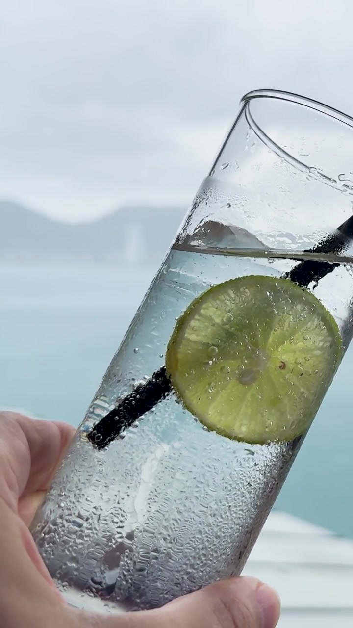 A hand holds a lime soda against a scenic ocean backdrop in Phuket, Thailand, capturing a serene and refreshing moment
