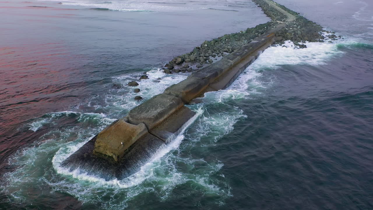 las olas rompen a través de las rocas en el embarcadero norte con perca gaviota en bandon, oregon