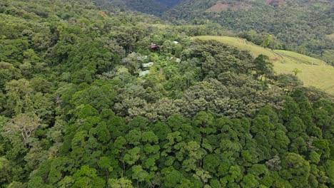 aerial view moving forward, descending shot, approaching house in the middle of hills of la tigra rain forest in costa rica