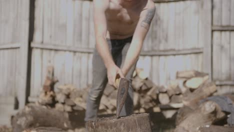 centered close up slow motion footage of a log being split by a axe wielding man