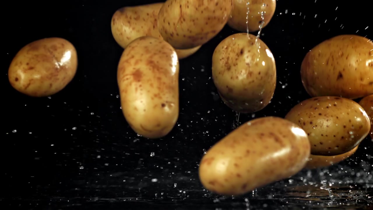 Patate fresche che cadono nell'acqua con schizzi su sfondo nero