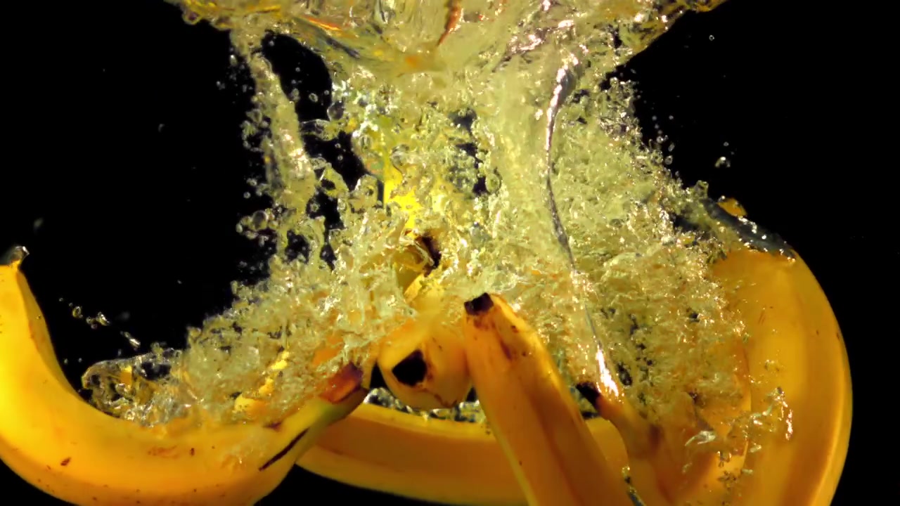 Ripresa al rallentatore di banane gialle che cadono nell'acqua