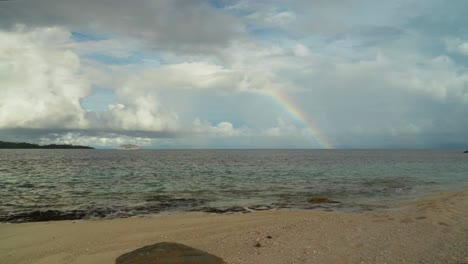 amazing beachfront view of the pacific ocean with cruiseship passing by and rainbow in background