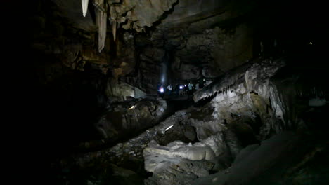 Menschen-Erkunden-Eine-Dunkle-Höhle-Mit-Taschenlampen-1