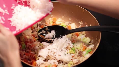 adding and mixing ingredients into fried rice